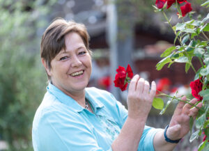 Eine Frau in einem Kontakt-Shirt hält eine Rose in der Hand.