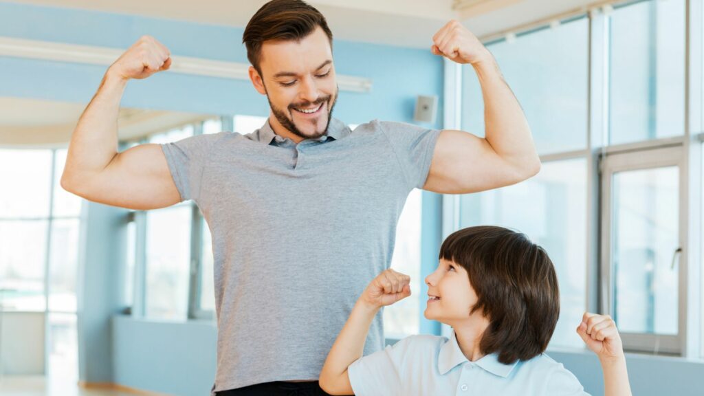Ein Mann und ein Junge stellen in einem Fitnessstudio ihre starken Muskeln zur Schau.