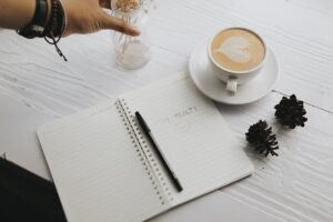 Ein Familienalltag mit Routinen: Eine Tasse Kaffee und ein Notizbuch auf einem Holztisch.