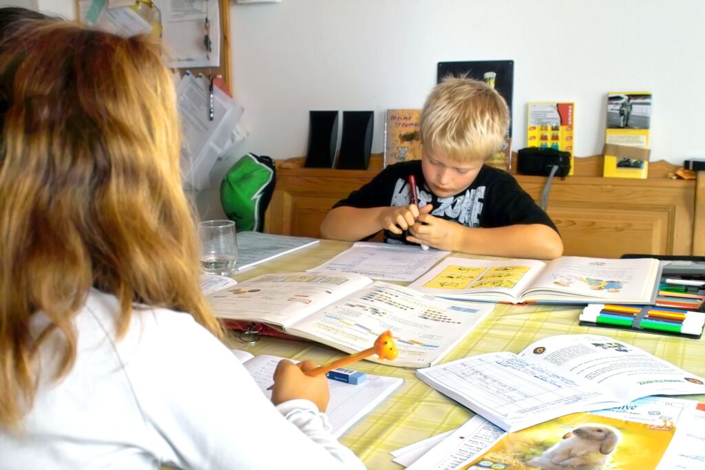 Ein Junge und ein Mädchen sitzen an einem Tisch und machen Hausaufgaben.
