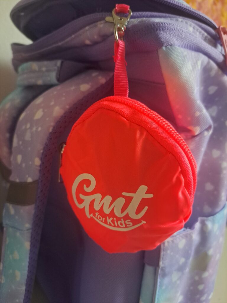 Roter „Gmt for Kids“-Beutel an einem lila Rucksack.