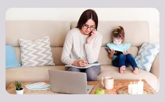 Eine entspannte Frau sitzt mit einem Laptop und ihrem Kind auf einer Couch.